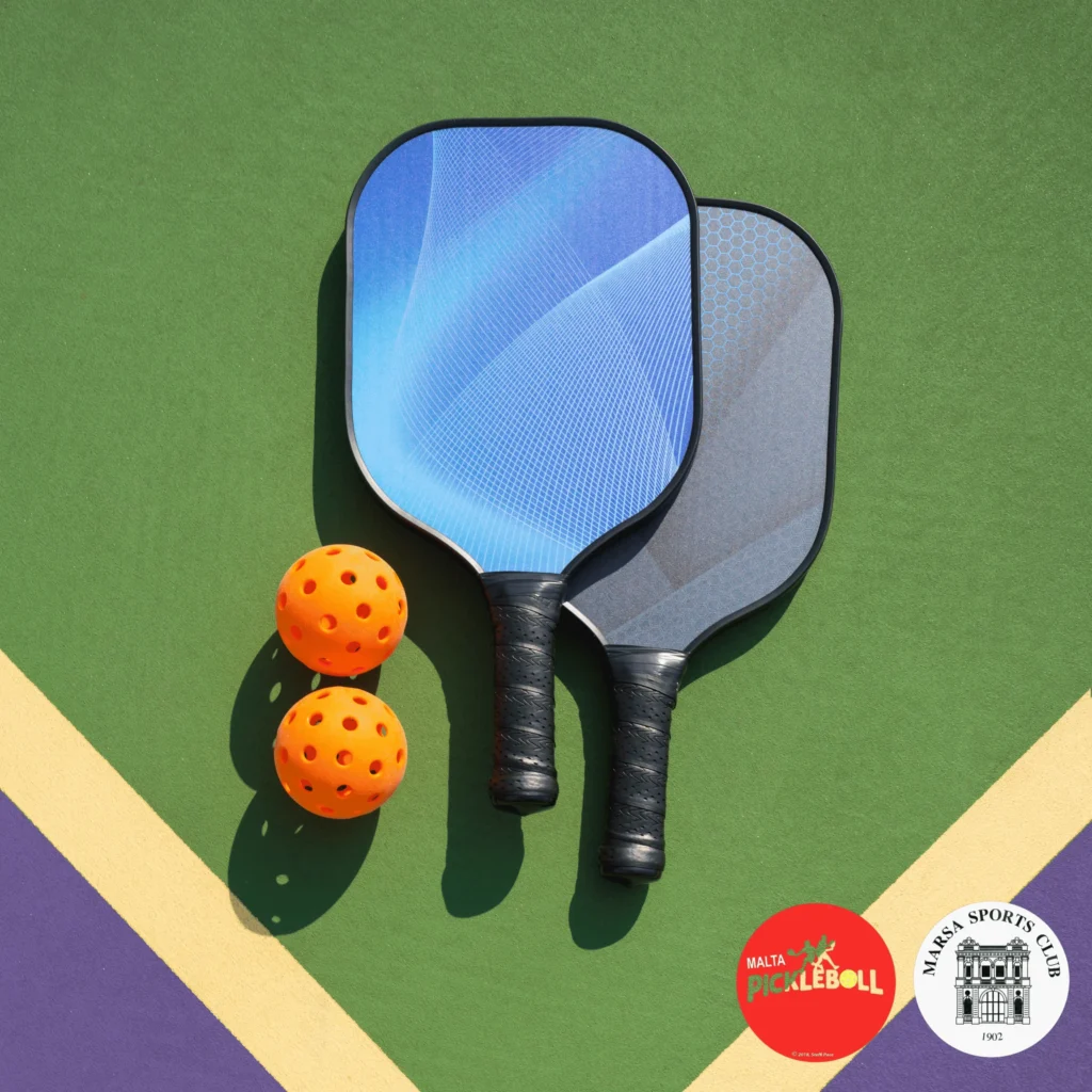 Two pickleball rackets with two pickleball balls on a green and purple court